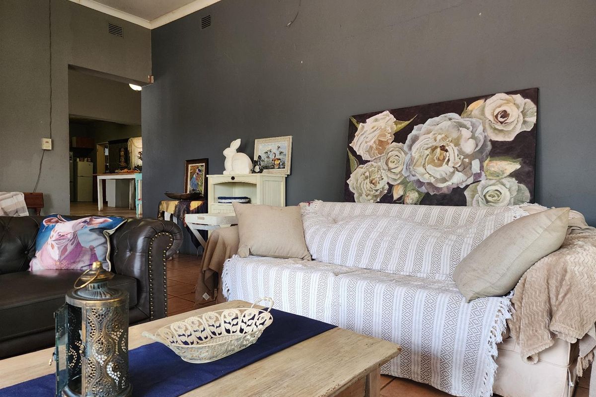 Spacious living room featuring tiled flooring and dark grey walls, with an open-plan flow leading into the adjacent kitchen area.