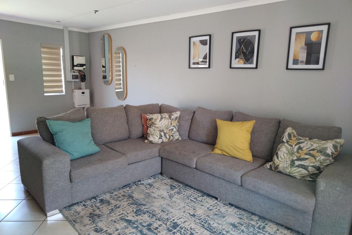 A comfortable living room featuring tiled flooring, recessed ceiling lighting, and a wall-mounted inverter system.