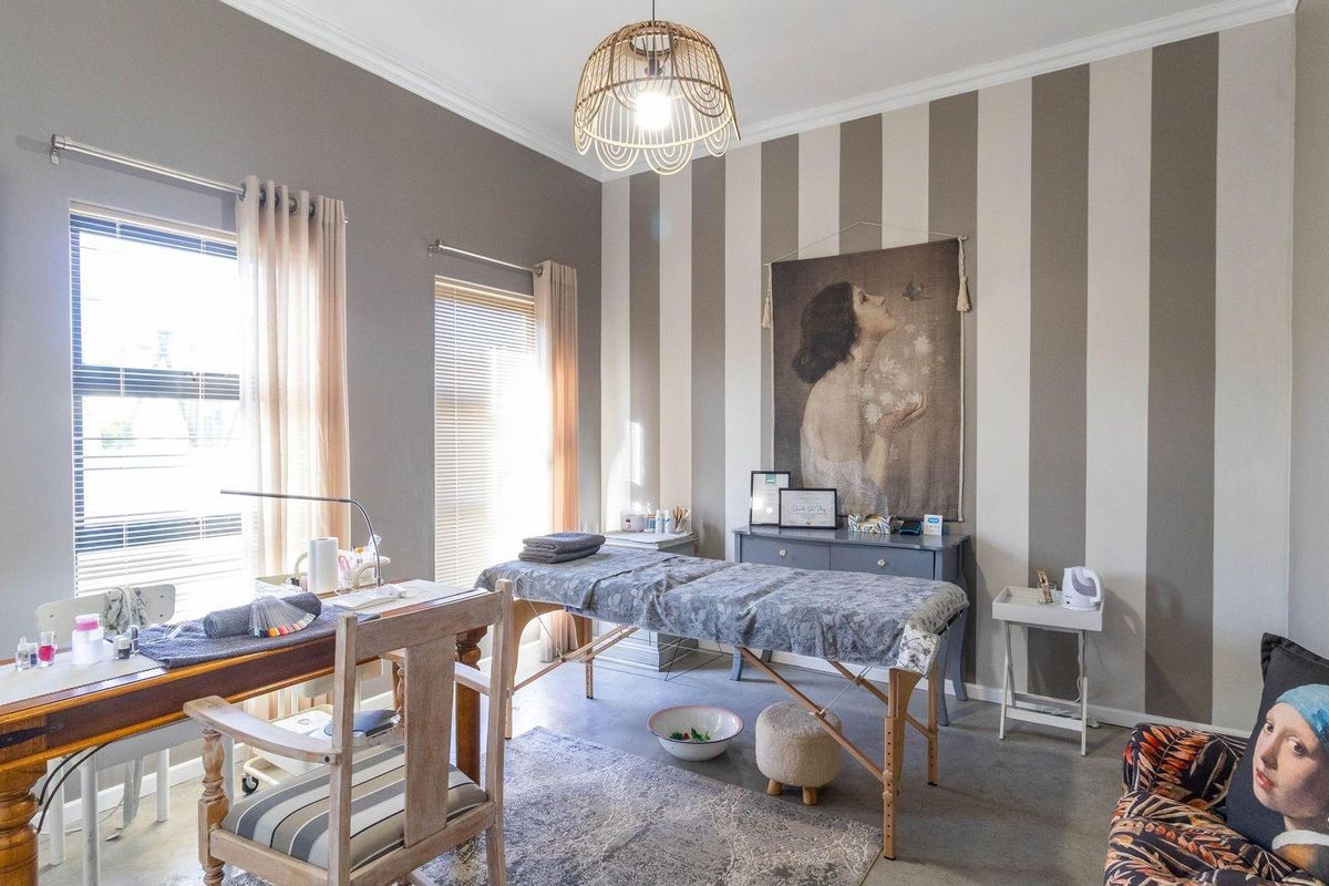 A well-maintained room featuring striped accent wall detailing, neutral paint finishes, and large windows providing natural light, suitable for a home office or studio.