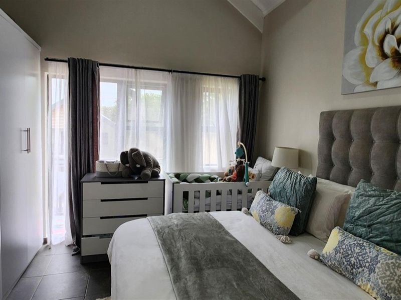 A well-lit bedroom featuring tiled flooring, a vaulted ceiling, and a large built-in wardrobe, offering a comfortable and functional living space.