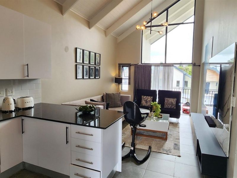 Modern open-plan living area featuring a sleek kitchen with granite countertops, gas cooktop, and a striking vaulted ceiling with large feature window.