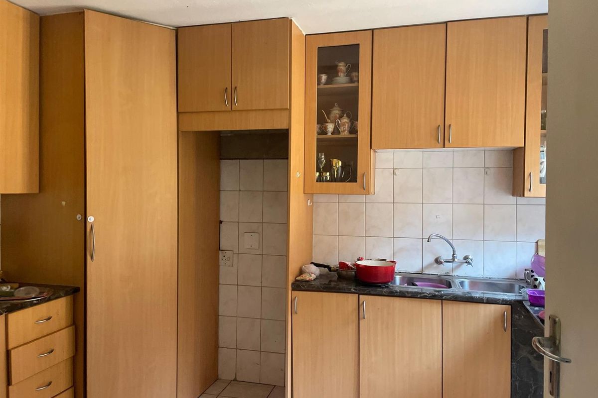 A functional kitchen featuring light wood-tone cabinetry, a double bowl sink, tiled backsplash, and dedicated space for appliances.