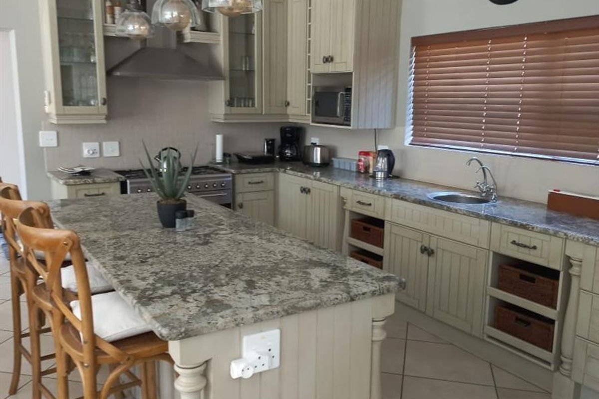 A well-appointed kitchen featuring granite countertops, shaker-style cabinetry, a central island with breakfast bar seating, and integrated stainless steel appliances.