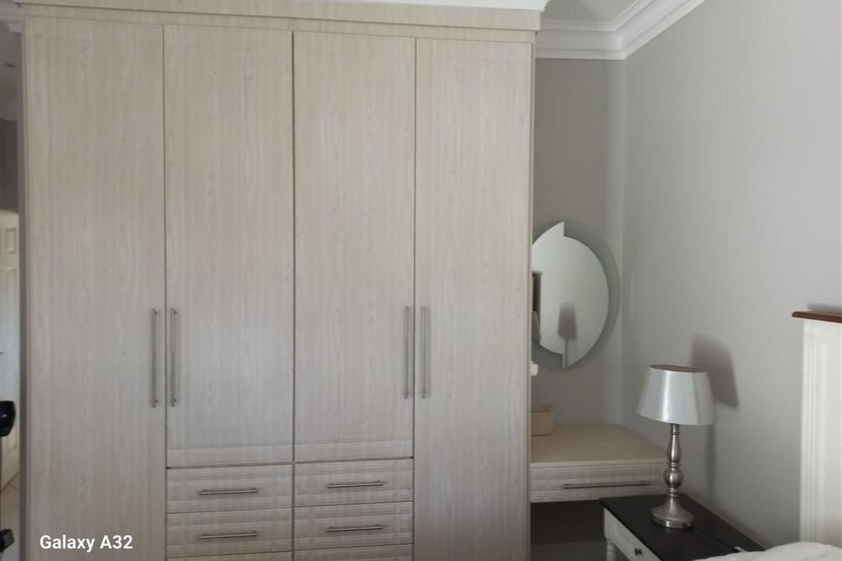 A bedroom featuring built-in light wood cabinetry with integrated drawers and a matching vanity area with a circular mirror.