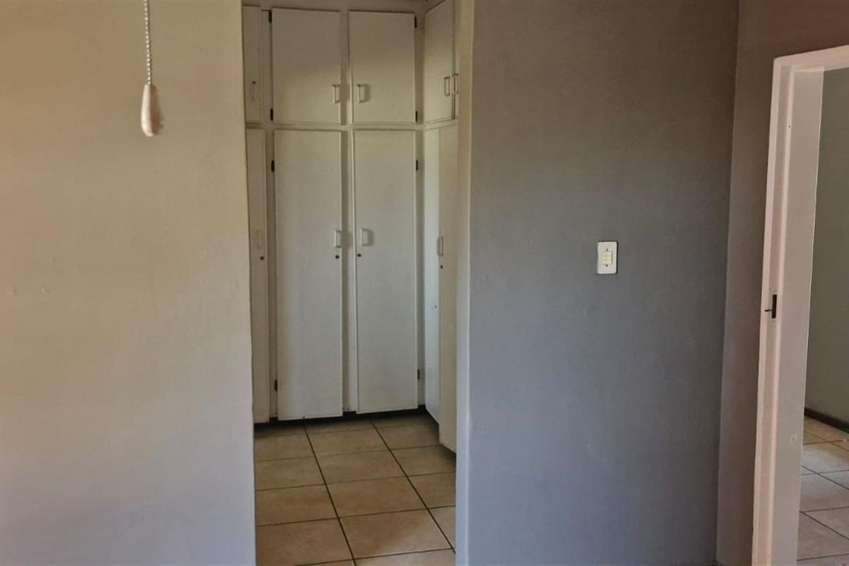 A bedroom featuring built-in cupboards and tiled flooring, offering a functional space ready for personalization.