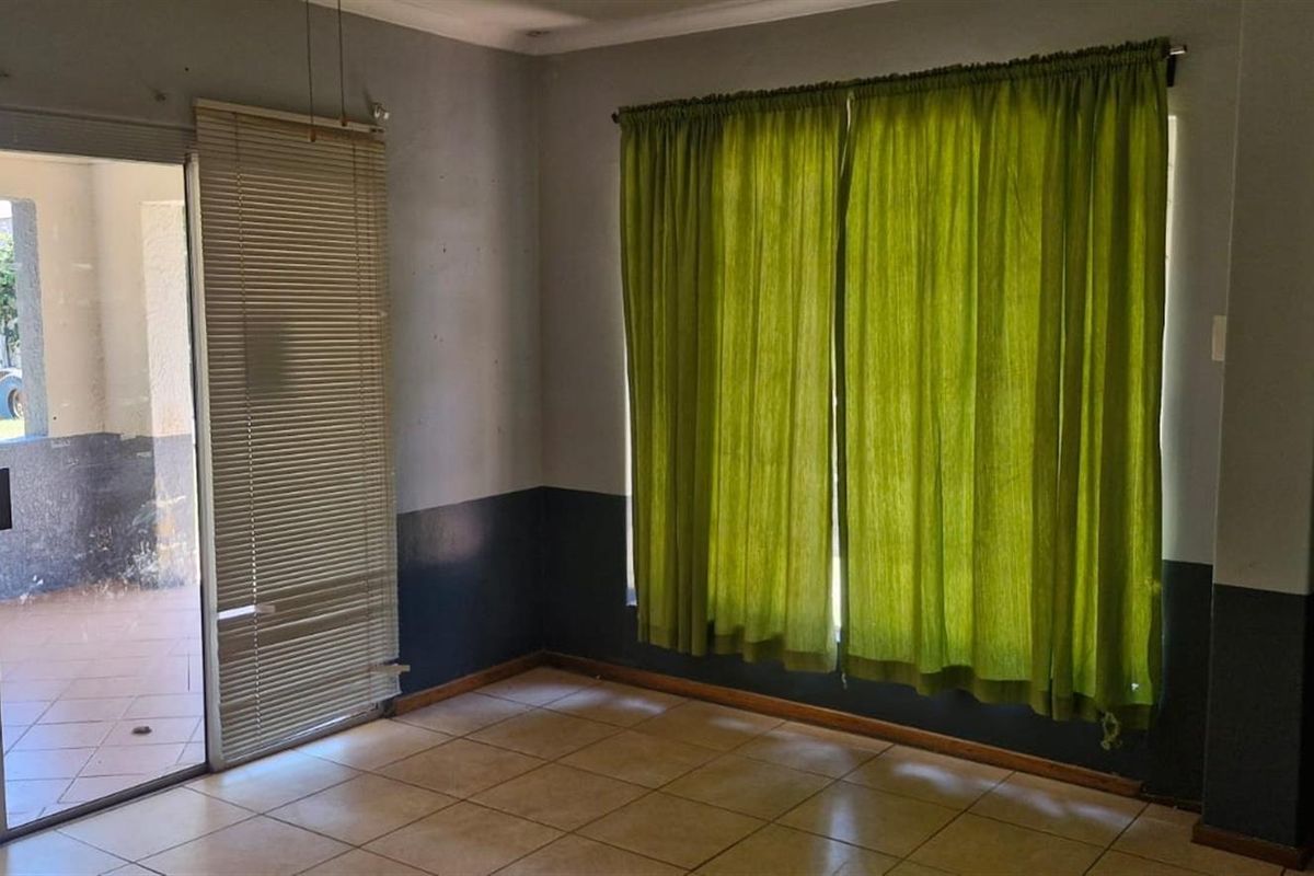 An empty living room featuring tiled flooring and a sliding glass door providing access to an outdoor patio area.