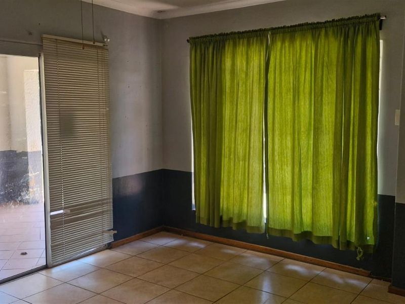 An empty living room featuring tiled flooring and a sliding glass door providing access to an outdoor patio area.