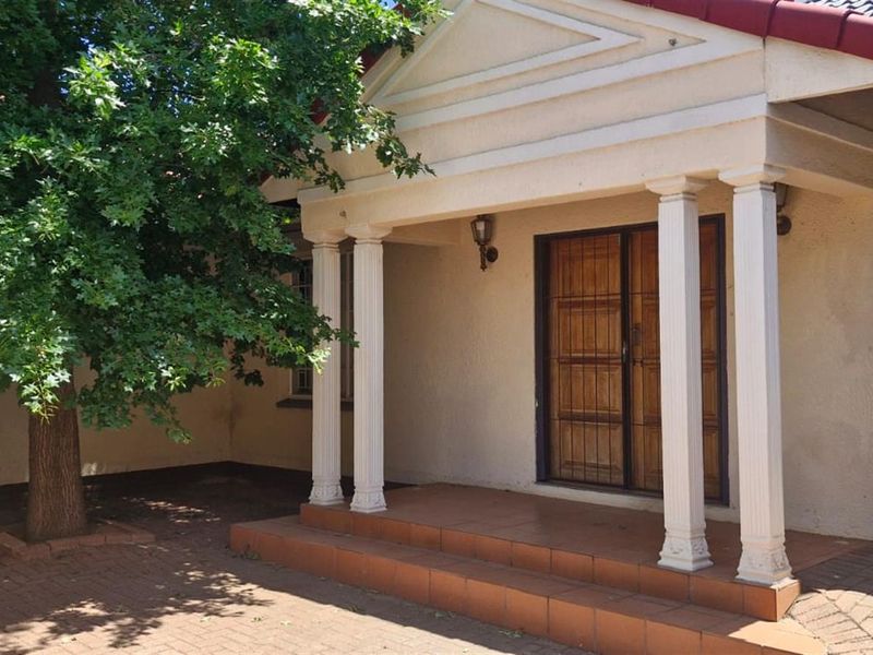 Front entrance featuring a covered porch with classical columns, tiled steps, and a timber door with security gate.