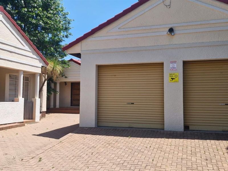 Front exterior view featuring a double garage with roller shutter doors, a paved driveway, and a covered porch entrance.