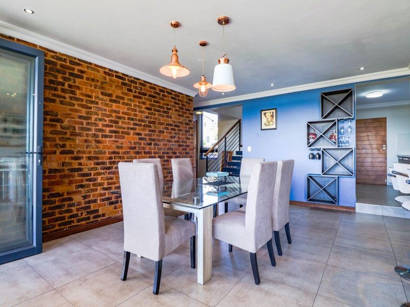 Dining area featuring an exposed brick wall, tiled flooring, built-in wine storage, and modern pendant lighting, creating a warm and inviting atmosphere.
