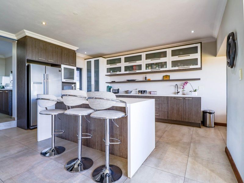 Modern kitchen featuring a central island with breakfast bar seating, ample built-in cabinetry, stone countertops, and sleek tiled flooring.