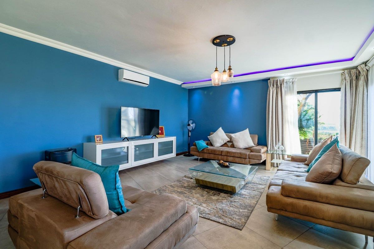 A well-maintained living room featuring tiled flooring, crown molding, recessed ceiling lighting, and a split-system air conditioner with access to an outdoor area.