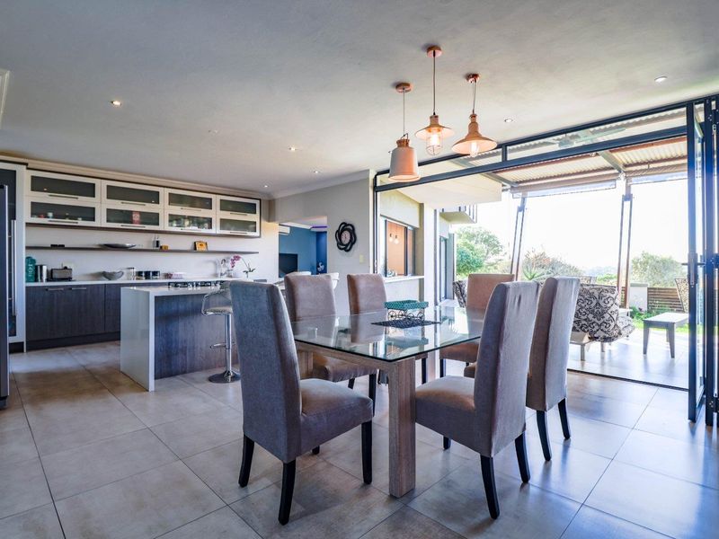Spacious open-plan kitchen and dining area featuring modern cabinetry, a central island, and large bi-fold doors opening to an outdoor patio.