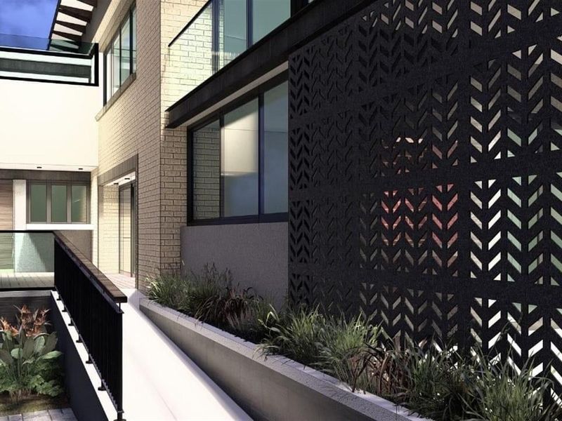 Modern exterior view featuring a decorative laser-cut metal privacy screen, glass balustrades, and integrated planter boxes along the building facade.