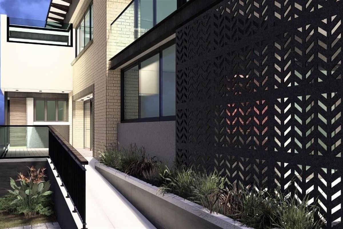 Modern exterior view featuring a decorative laser-cut metal privacy screen, glass balustrades, and integrated planter boxes along the building facade.