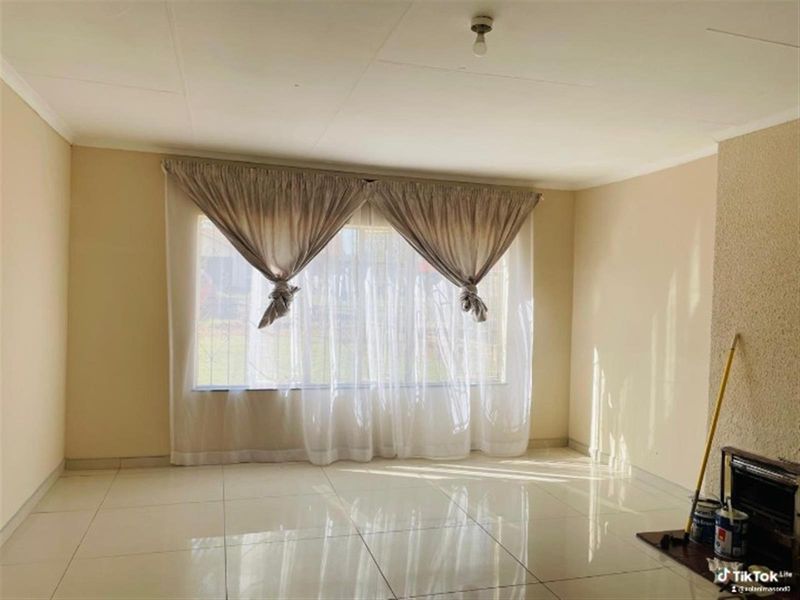 A bright, empty living room featuring polished tile flooring and a built-in fireplace, offering a clean canvas for interior design.