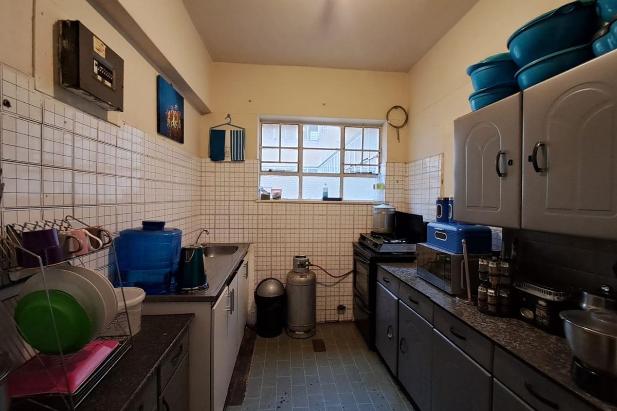 A compact, functional kitchen featuring tiled walls, laminate countertops, and built-in cabinetry with a gas stove connection.