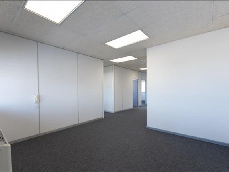 A vacant, open-plan office space featuring neutral partition walls, carpeted flooring, and recessed ceiling lighting, offering a clean and functional workspace.