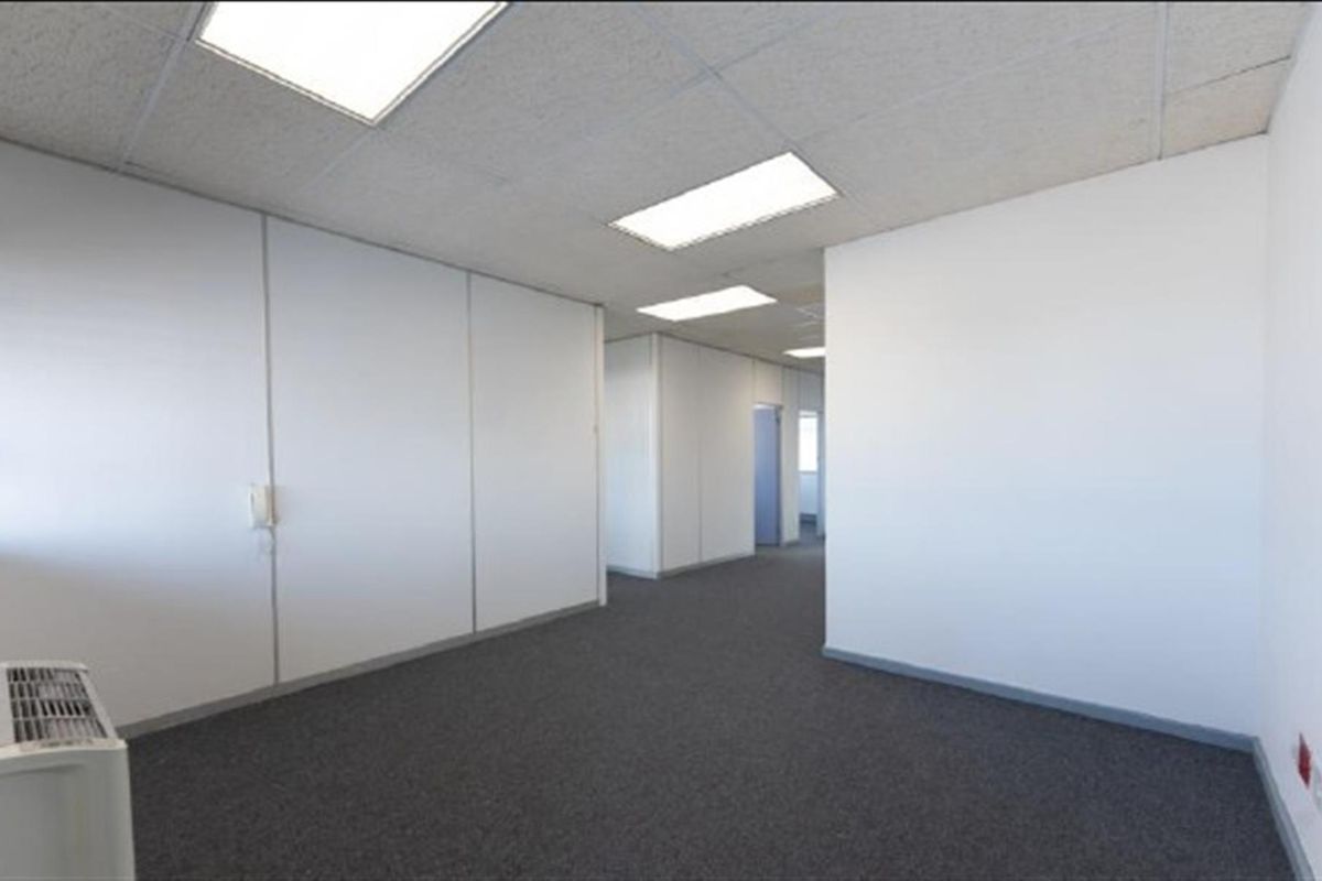 A vacant, open-plan office space featuring neutral partition walls, carpeted flooring, and recessed ceiling lighting, offering a clean and functional workspace.
