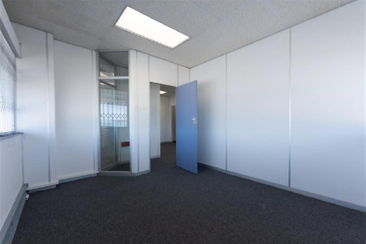 A vacant office space featuring modular partition walls, recessed ceiling lighting, and dark carpeting, providing a clean and functional professional environment.