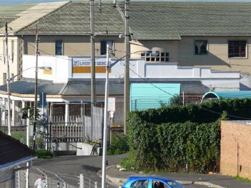 An elevated view of the office property exterior, featuring a tiled roof, paved access, and perimeter metal fencing.