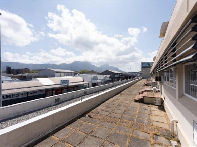 An elevated outdoor terrace area featuring paved flooring, a protective parapet wall, and views over the surrounding commercial district.