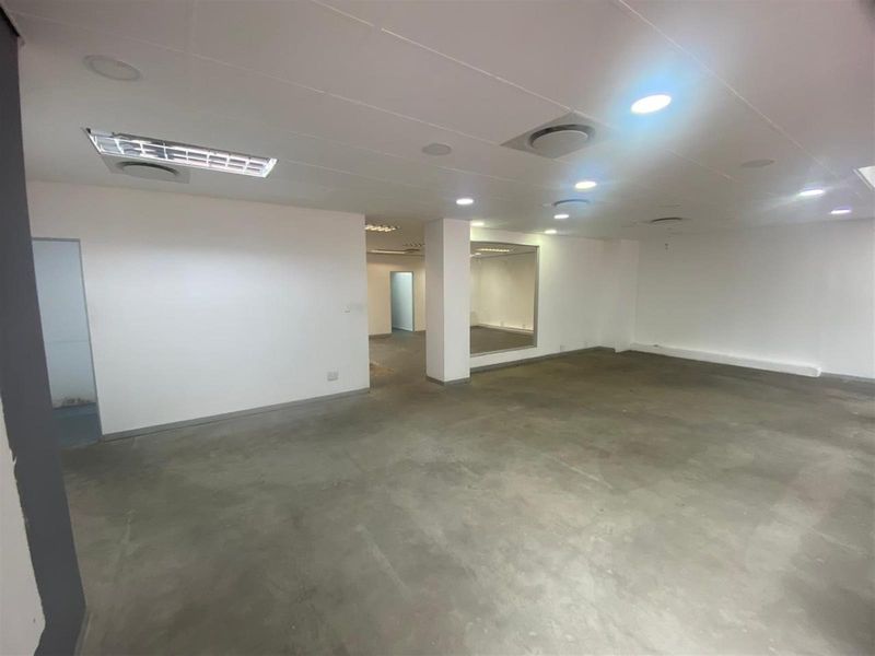 Spacious open-plan retail or office area featuring concrete flooring, recessed ceiling lighting, and integrated air conditioning vents.