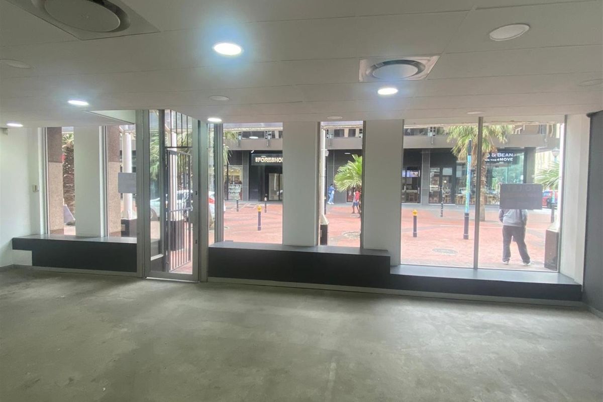 An open-plan retail space featuring large display windows, recessed lighting, and concrete flooring, offering excellent visibility for a storefront or showroom.