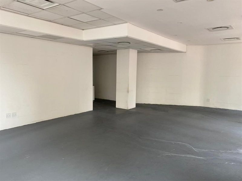 An empty open-plan retail space featuring a suspended ceiling, recessed lighting, and durable concrete flooring, ready for custom fit-out.