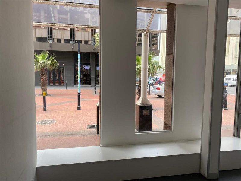 A view from inside a retail space looking out onto a paved pedestrian plaza and street area through large display windows.