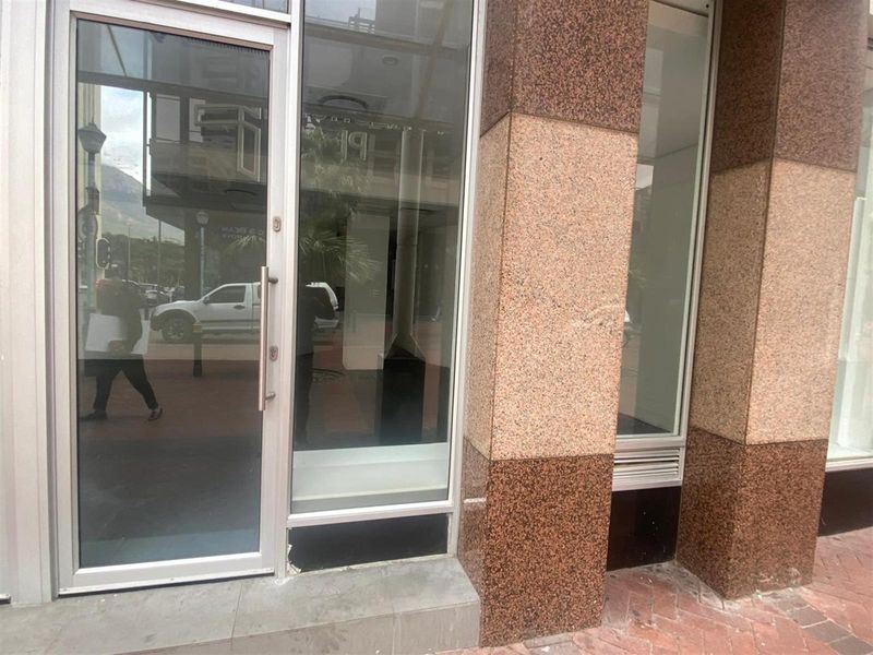 Street-level retail storefront featuring granite facade cladding, large display windows, and a modern aluminium-framed glass entrance door.