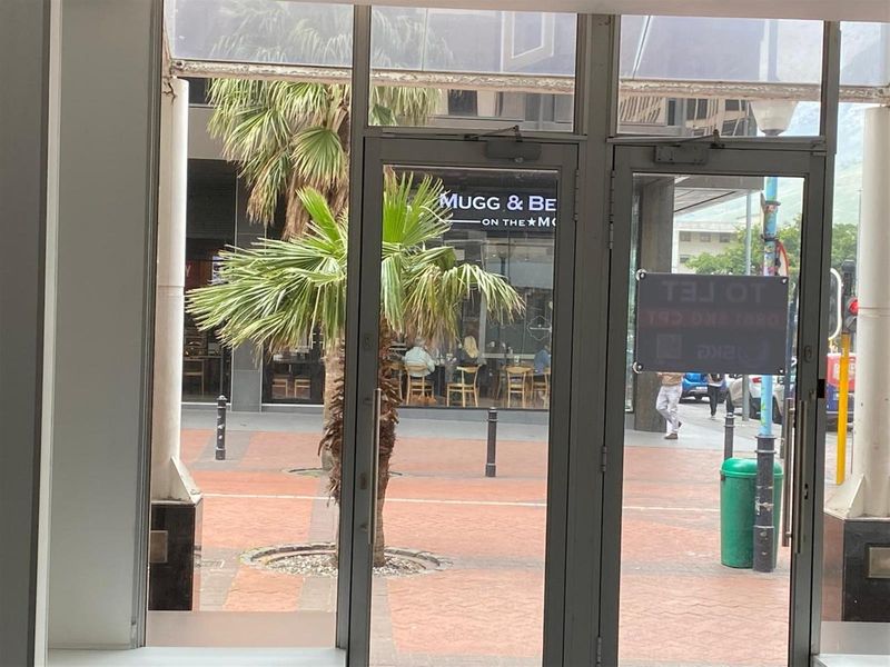 View from inside a retail unit looking out onto a paved pedestrian street and neighbouring commercial storefronts.
