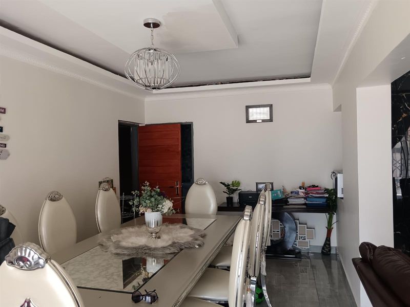 Dining room featuring tiled flooring, crown molding, and a decorative pendant light fixture, with an unfinished ceiling edge requiring attention.