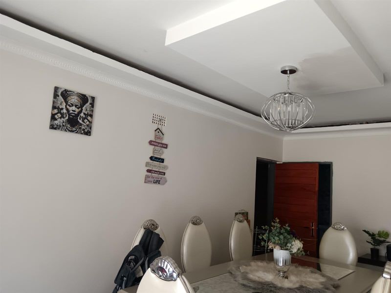 Dining room featuring a recessed ceiling with decorative cornice and a modern pendant light fixture.