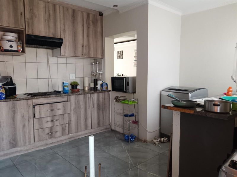Functional kitchen featuring wood-look laminate cabinetry, granite countertops, gas hob, and tiled flooring. Requires minor finishing touches to cabinetry and flooring.