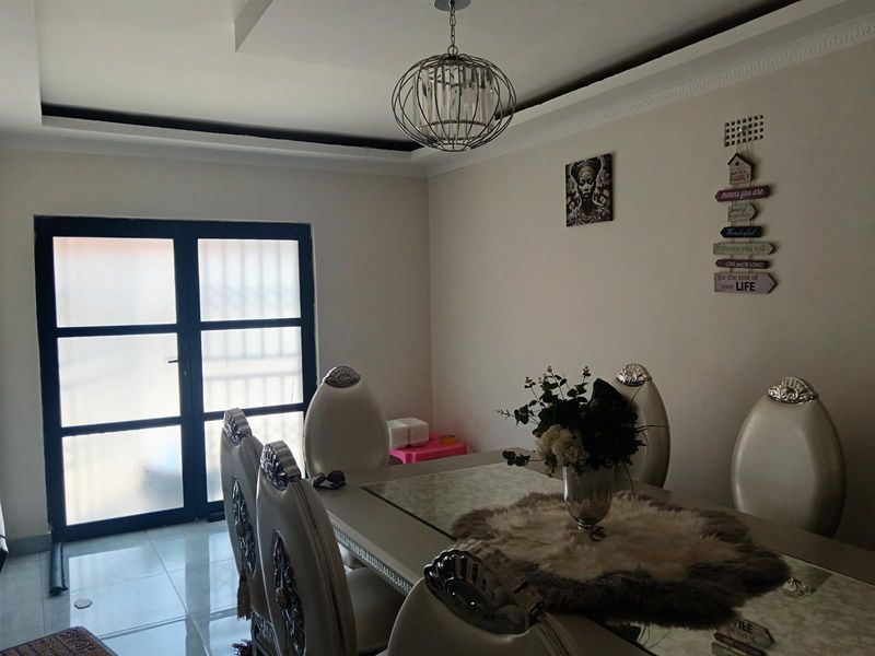 A dining room featuring tiled flooring, decorative ceiling coving, and a double glass door providing access to the exterior.