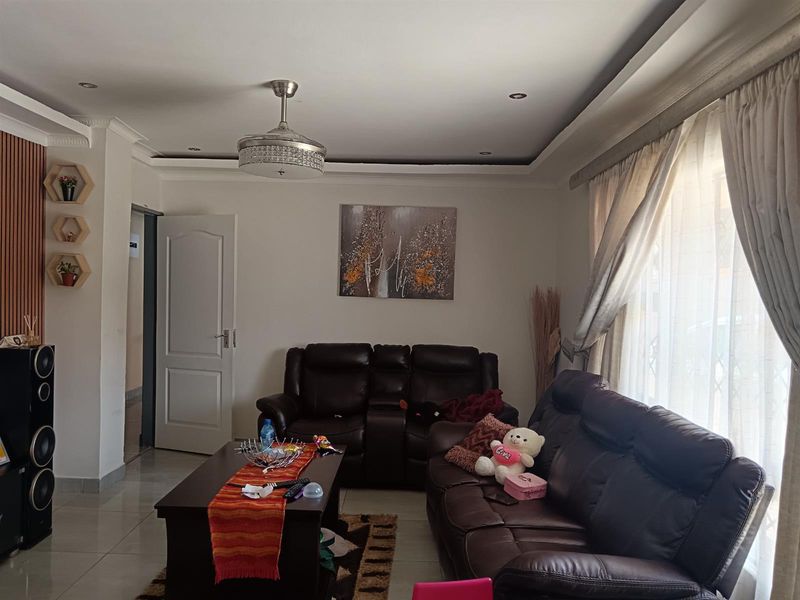A comfortable living room featuring tiled flooring, recessed ceiling lighting, a ceiling fan, and decorative wall paneling, creating a welcoming and functional space.