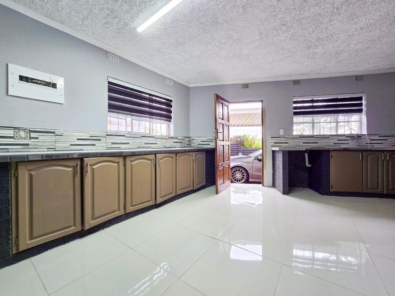 A functional kitchen space featuring tiled flooring, built-in cabinetry, and a tiled splashback, offering a blank canvas for modern updates.