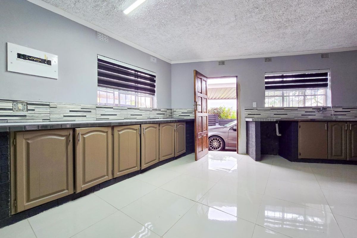 A functional kitchen space featuring tiled flooring, built-in cabinetry, and a tiled splashback, offering a blank canvas for modern updates.