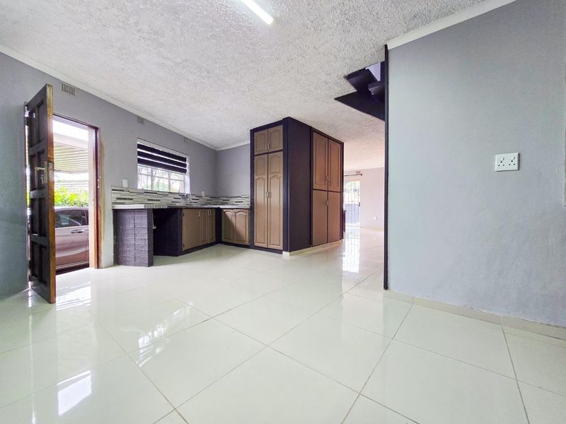 An open-plan kitchen area featuring built-in cabinetry, tiled flooring, and direct access to the exterior, offering a functional space ready for updates.