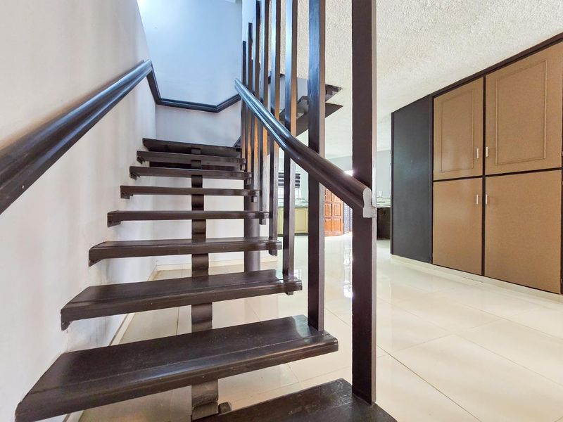 A bright hallway featuring an open-tread wooden staircase with a matching handrail and integrated floor-to-ceiling storage cabinetry.