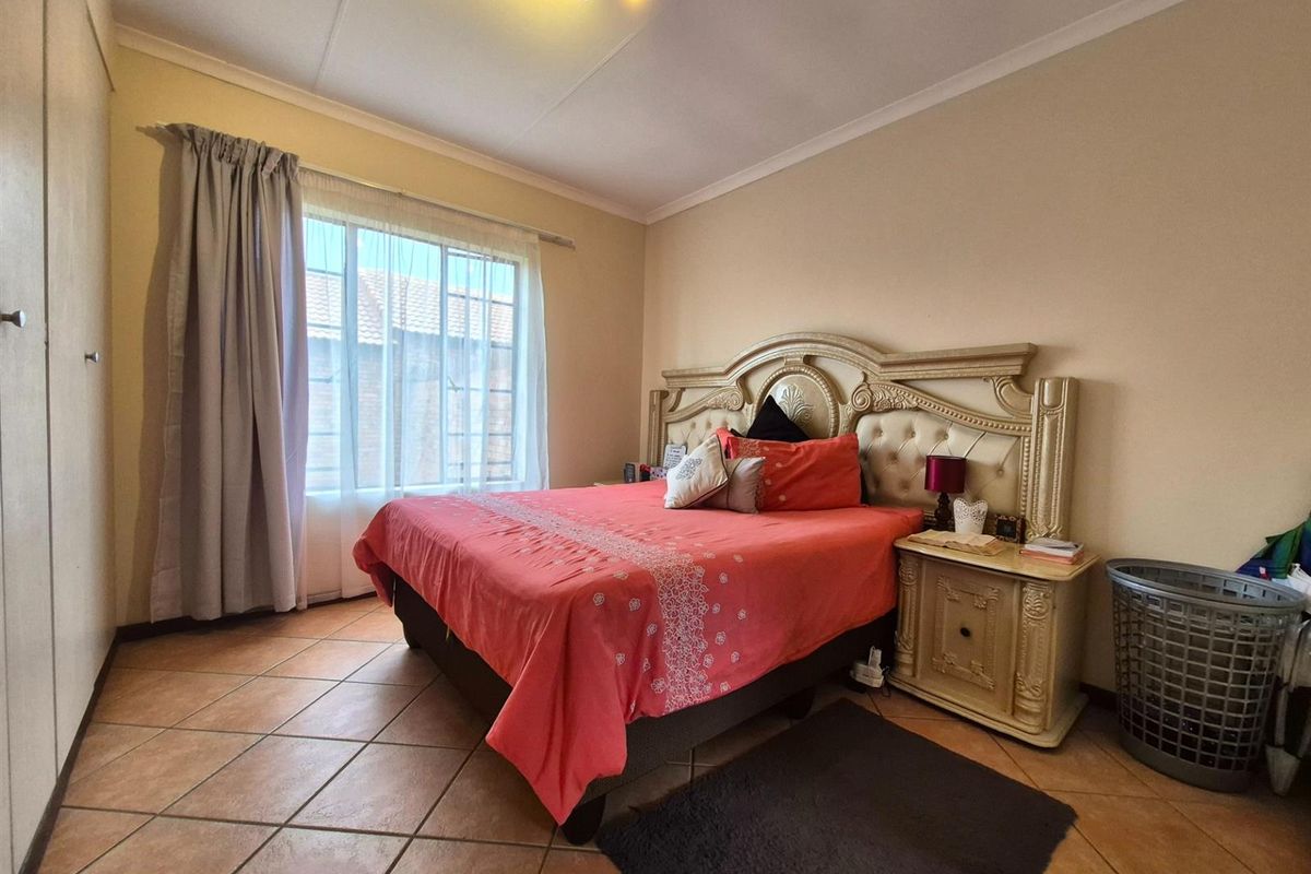 A bedroom featuring tiled flooring, built-in cupboards, and a window with curtain tracks.