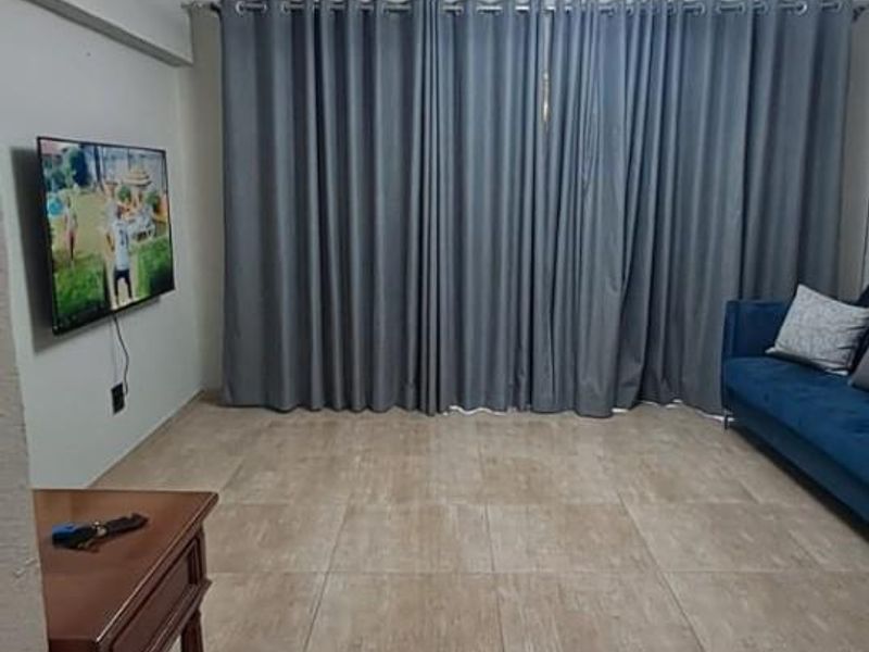 A well-maintained living room featuring large format floor tiles, decorative ceiling coving, and a contemporary circular pendant light fixture.