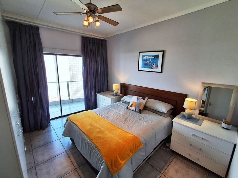 A bedroom featuring tiled flooring, a ceiling fan, and a sliding glass door providing access to an outdoor balcony.