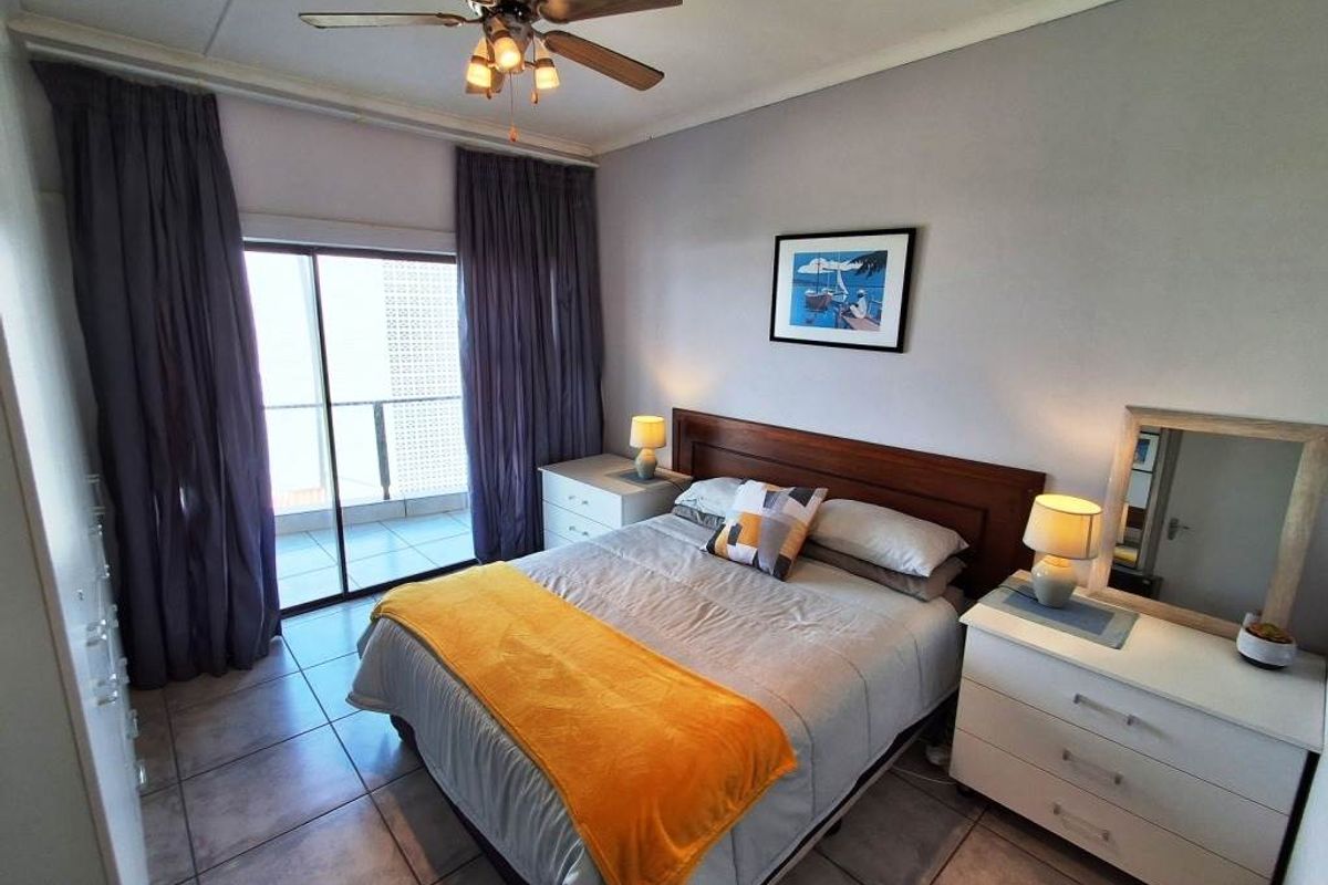 A bedroom featuring tiled flooring, a ceiling fan, and a sliding glass door providing access to an outdoor balcony.