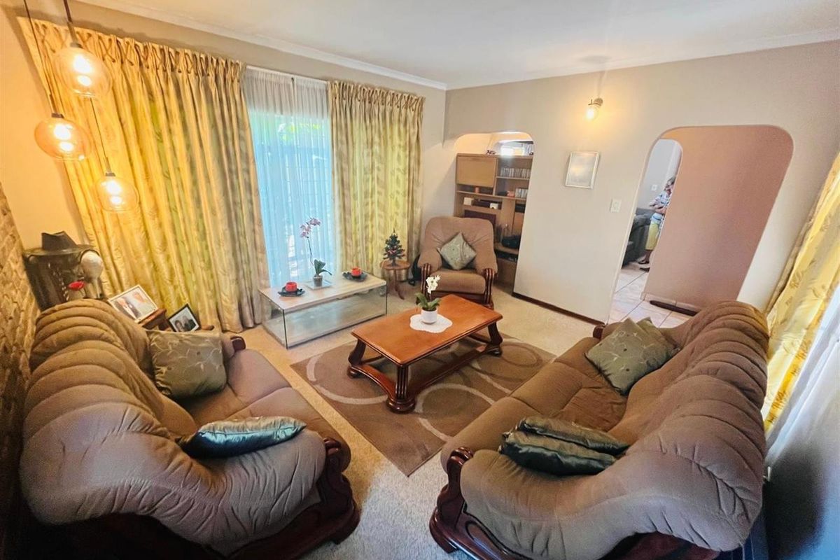 A comfortable living room featuring arched doorways, neutral wall tones, and large windows with floor-to-ceiling curtains, providing a warm and inviting atmosphere.