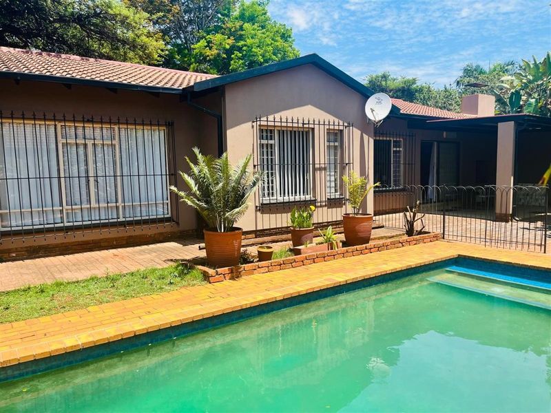Rear view of the house featuring a swimming pool, paved patio area, and security bars on windows.