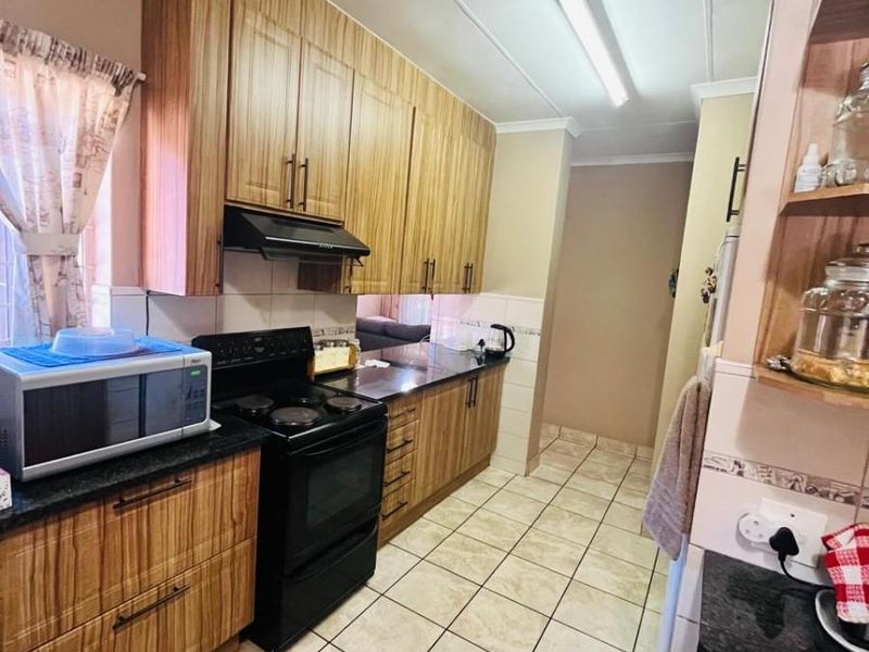A functional kitchen featuring wood-grain cabinetry, dark granite countertops, a built-in stove with extractor fan, and tiled flooring.
