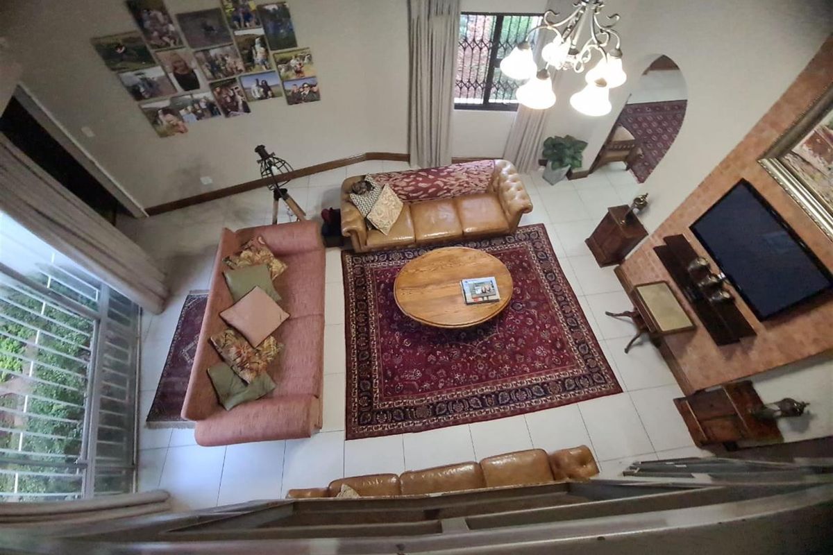 High-angle view of a spacious living room featuring tiled flooring, a decorative chandelier, and a built-in media wall.