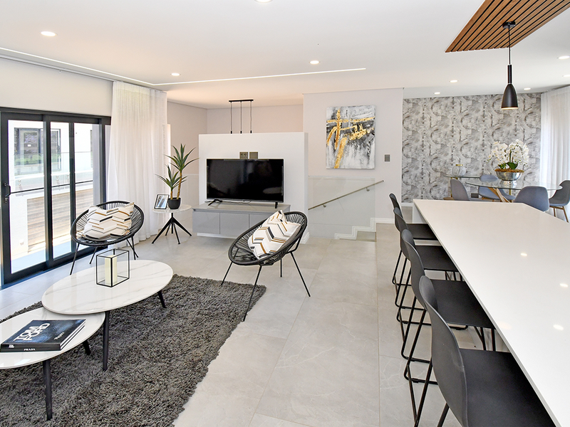 Modern open-plan living and dining area featuring large format floor tiles, a kitchen island, and contemporary architectural lighting details.